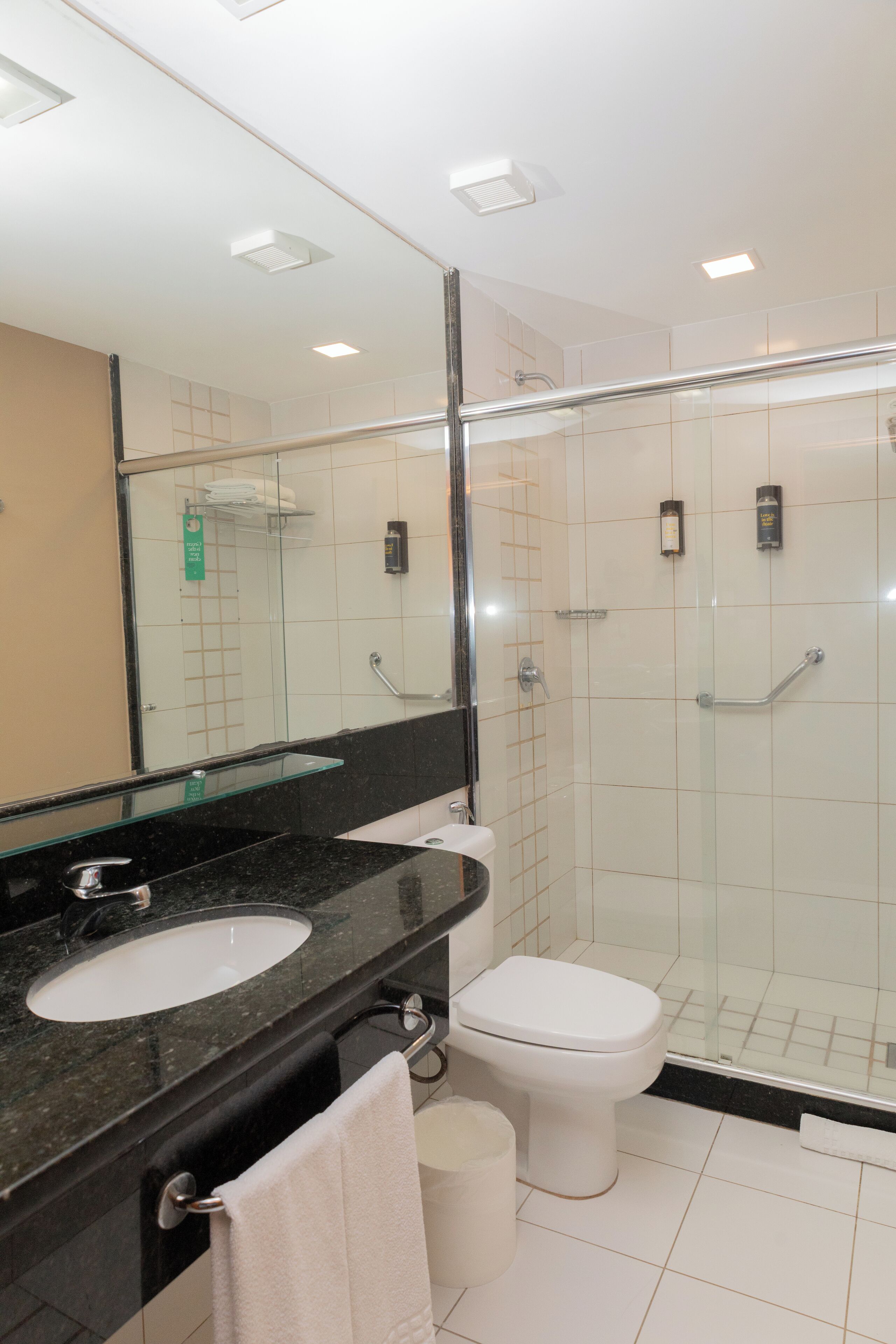 A modern bathroom with a glass-enclosed shower, a black countertop sink, and a white toilet.