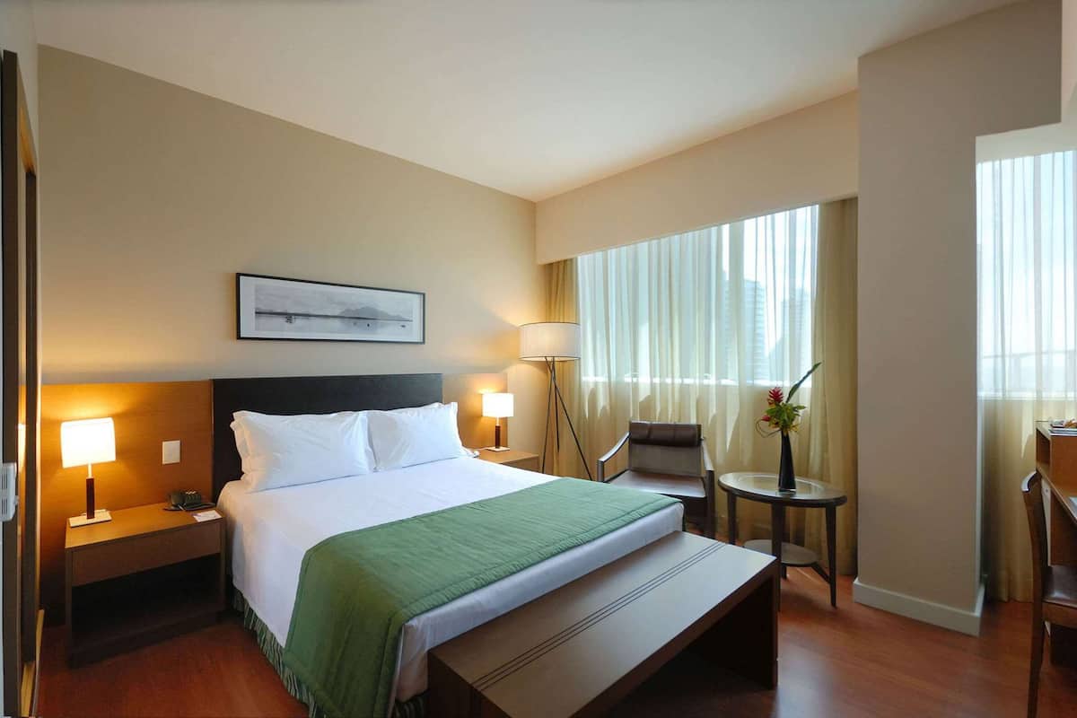 Comfortable retreat with a neatly made bed, bedside table, and desk near a window.
