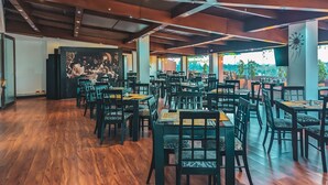 A spacious restaurant with high ceilings, wooden floors, and a mural on the wall. Tables and chairs are neatly arranged, and the restaurant has large windows allowing natural light. - Hotel Charlotte Suite 26 (Bogotá)
