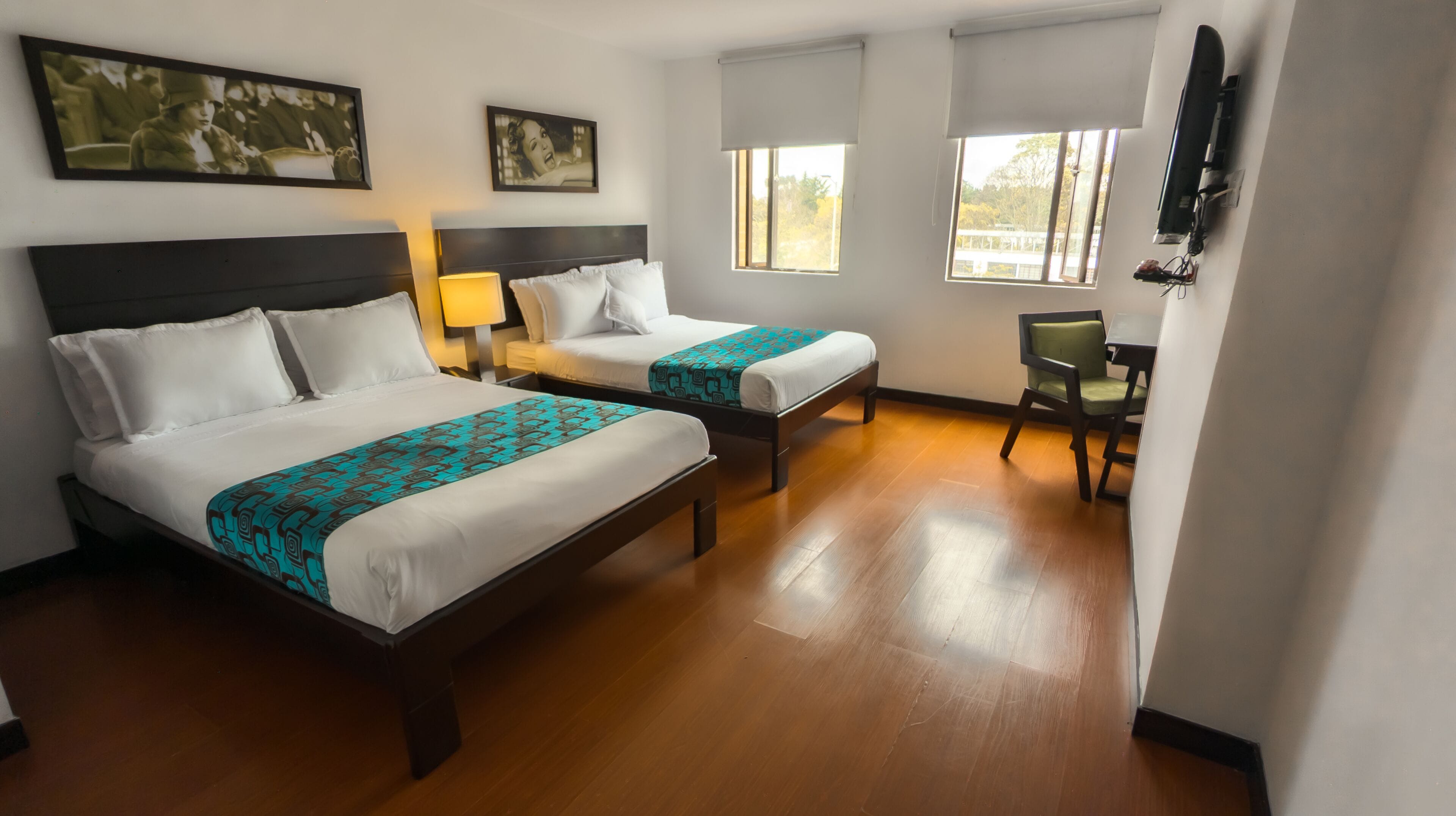 Habitación de hotel con dos camas, un escritorio y una silla.