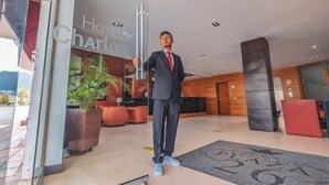 A man in a suit standing at the entrance of a hotel named 'Hotel Charlie'. - Hotel Charlotte Suite 26 (Bogotá)