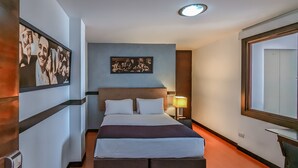 A hotel room with a bed, a desk, a lamp, and artwork on the walls. - Hotel Charlotte Suite 26 (Bogotá)