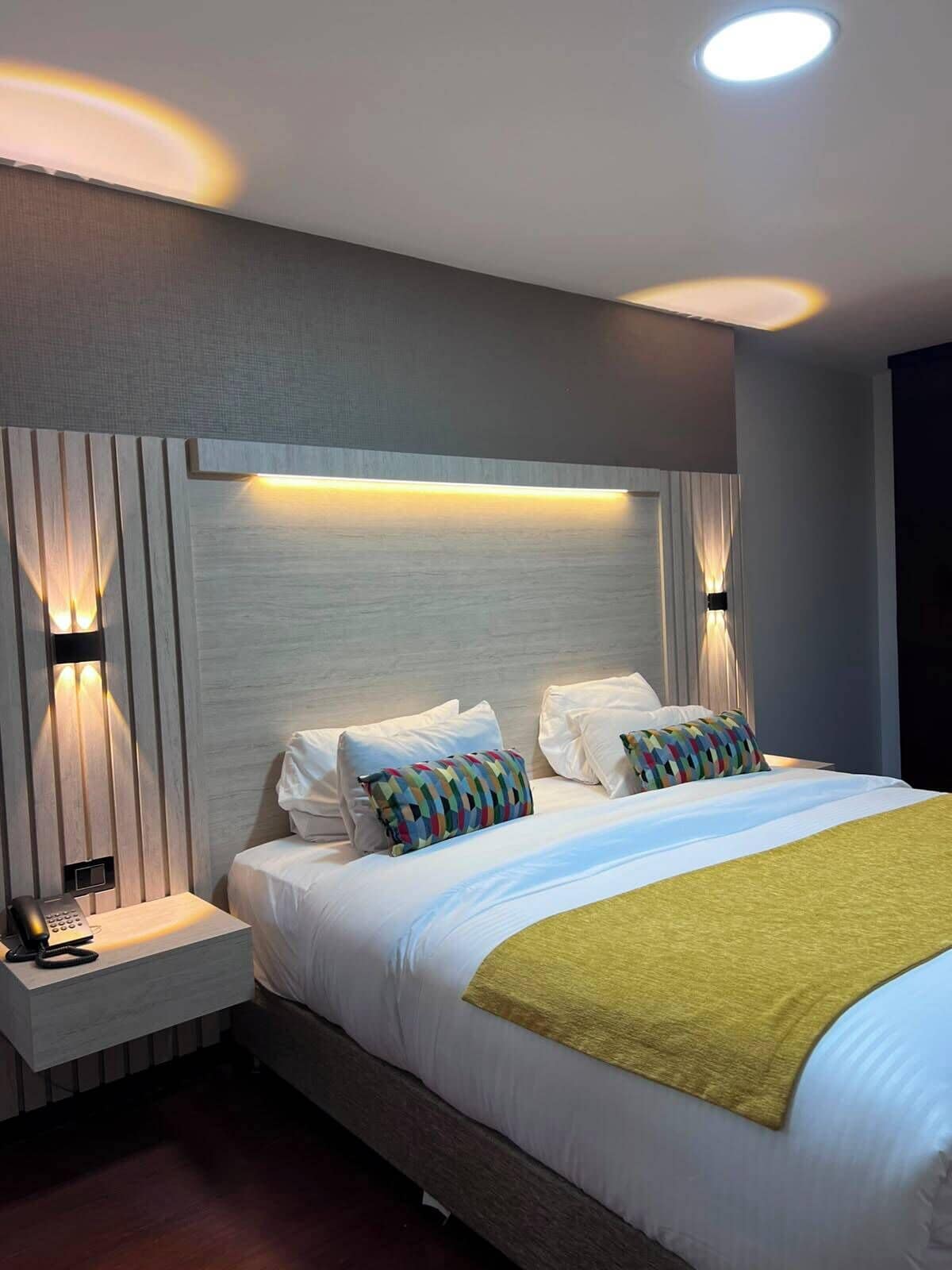 Quarto de hotel com cama, mesas de cabeceira e telefone.