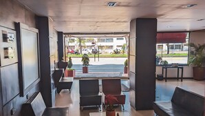 A lobby with a reception desk, seating area, and a view of the street. - Hotel Charlotte Suite 26 (Bogotá)