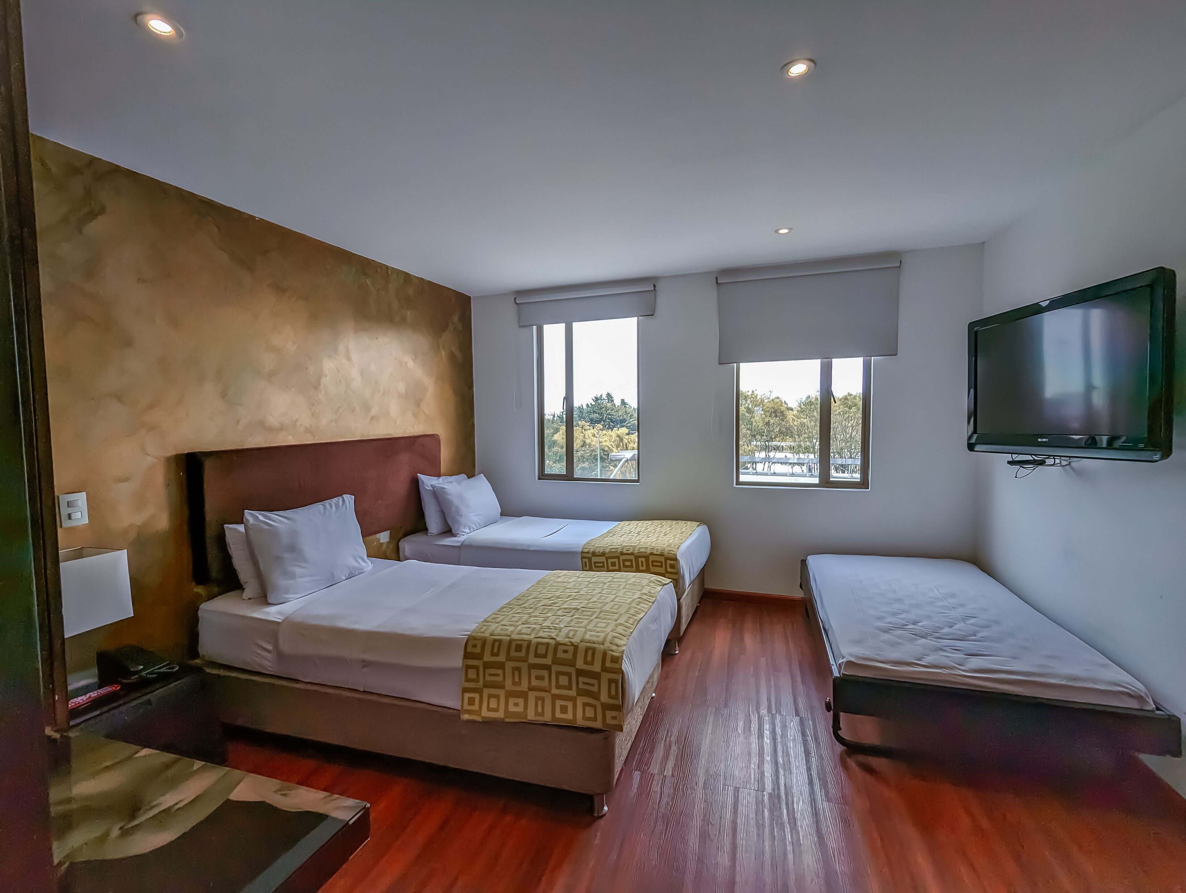 A hotel room with two beds, a TV, and large windows.