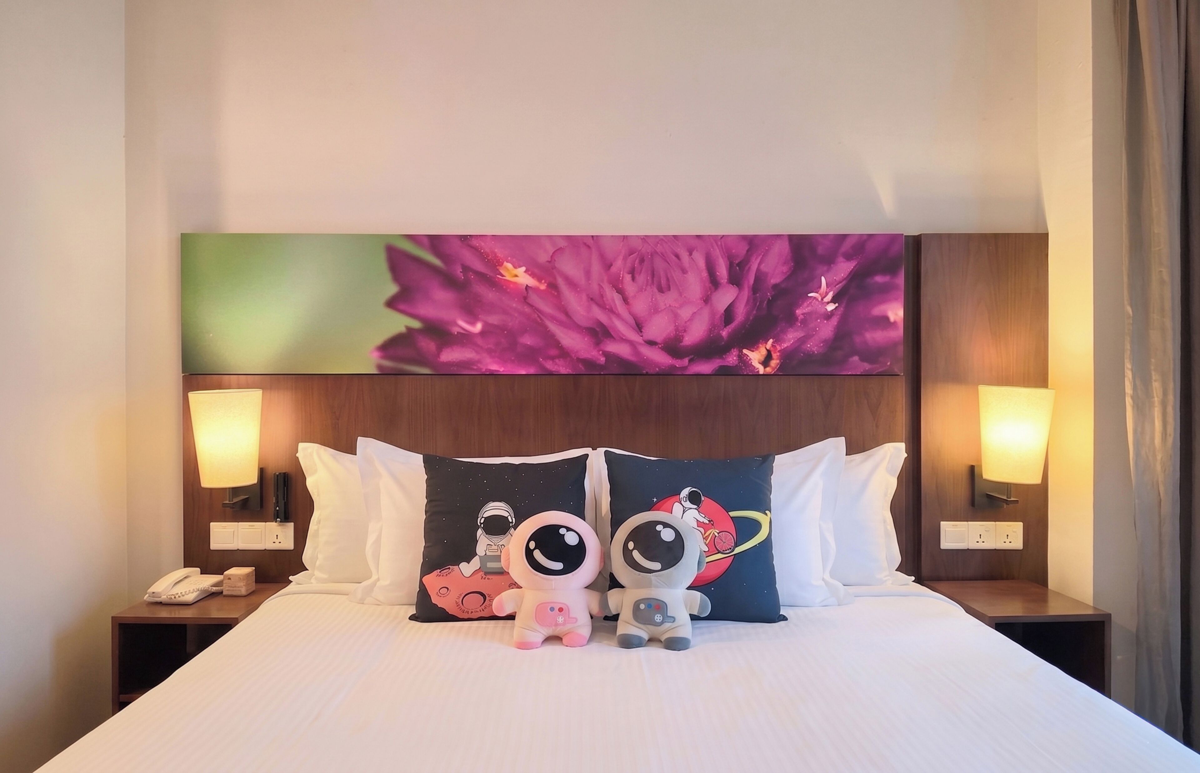Habitación de hotel con una cama grande, dos mesitas de noche, un teléfono y almohadones decorativos.