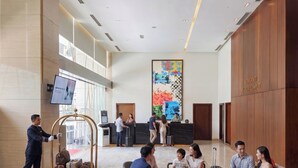 A hotel lobby with a reception desk, a large abstract painting, and a luggage cart. - Somerset Kuala Lumpur (Kuala Lumpur)