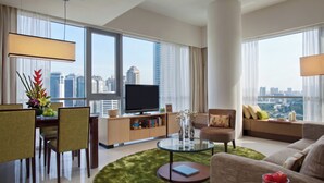 A modern hotel room with a flat-screen TV, a sofa, a dining area with chairs, a glass coffee table, and a view of the city skyline. - Somerset Kuala Lumpur (Kuala Lumpur)