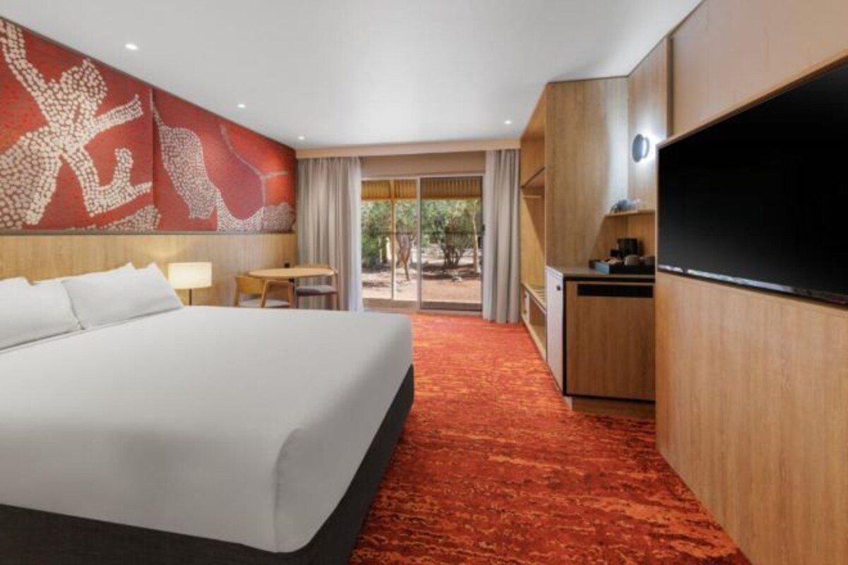 Une chambre d’hôtel avec un grand lit, un bureau, une télévision et une vue sur l’extérieur.