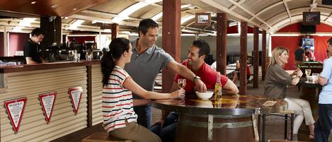 A bar area with wooden stools, a counter, and a large wooden barrel.