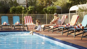 A swimming pool area with lounge chairs and a tiled deck. - The Outback Hotel (Yulara)