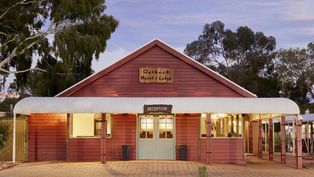 A red building with a sign reading "Outback Hotel & Lodge" and a "Reception" sign. - The Outback Hotel (Yulara)