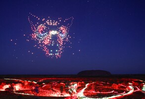 Cielo nocturno con un fondo estrellado y una gran estructura iluminada que se asemeja a un árbol o diseño abstracto.
