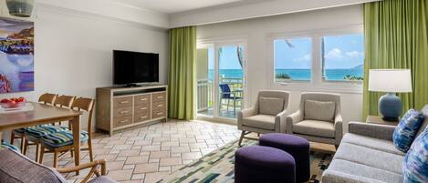 Habitación de hotel con balcón, zona de comedor, sofá y televisor.