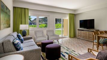 A modern living room with a sofa, chairs, ottomans, a television, and a dining area.