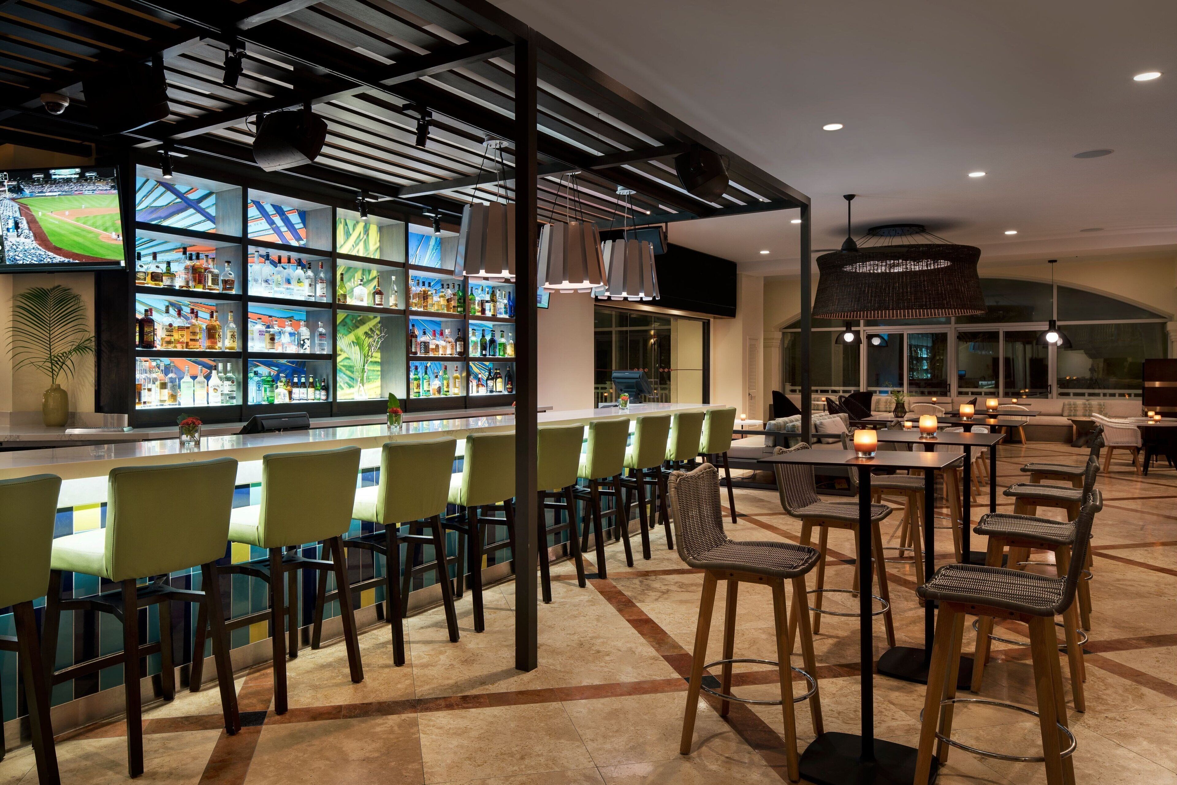 Un espace bar doté d’un long comptoir, de nombreuses étagères à bouteilles et de plusieurs options d’assises, notamment des tabourets et des chaises de bar.