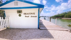 A white and blue boat house named "SEACOVE" with a wooden dock extending into a body of water. - Floating Sea Cove Resort & Marina (Marathon)