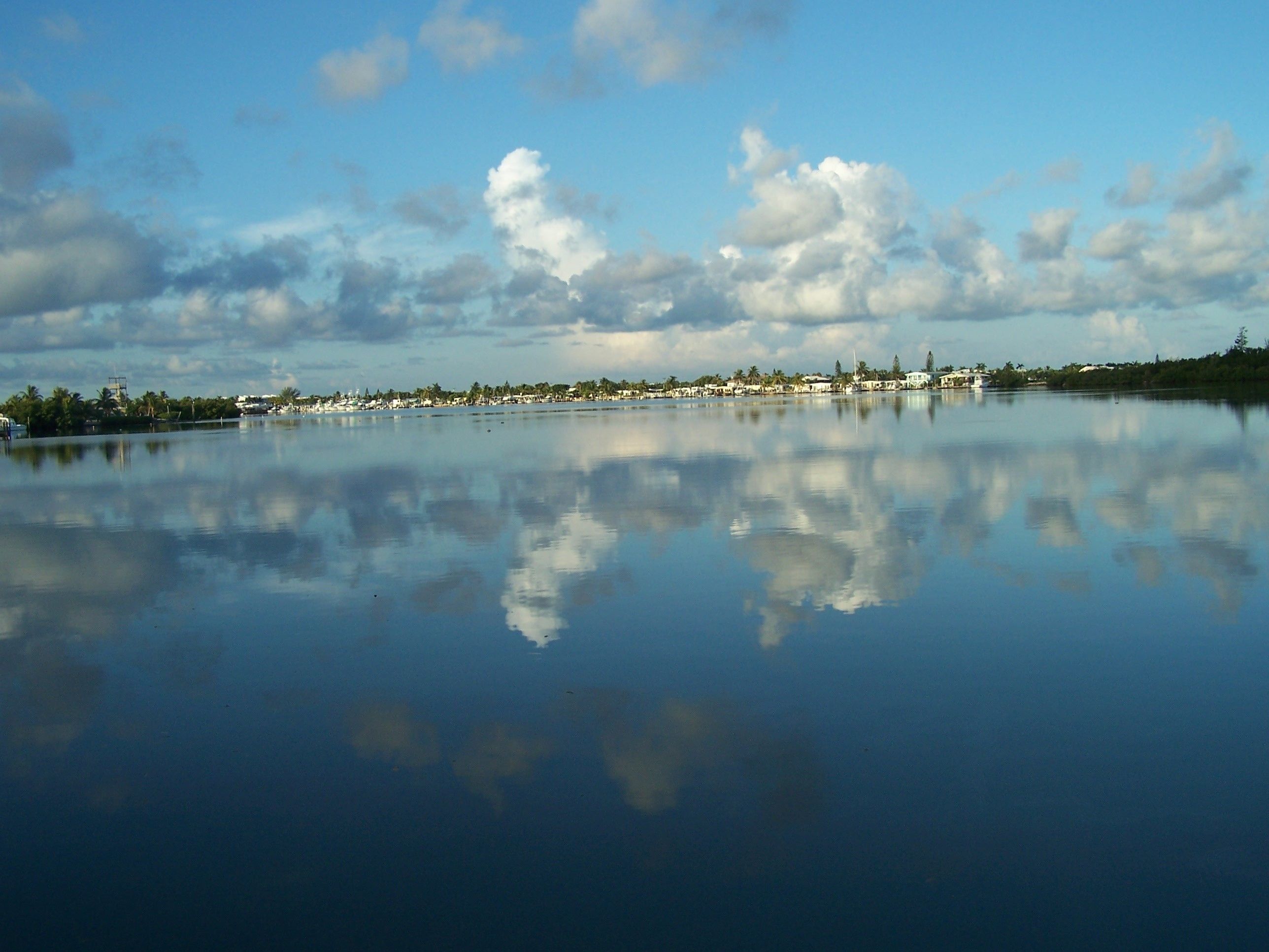 A calm lake with a clear reflection of the sky and clouds.