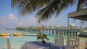A table set for dining with a view of the sea and a pier in the background. - Hof Gorei Beach Resort (Samal)
