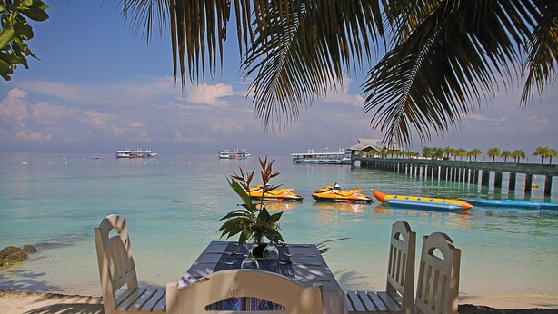 A beachside table with a view of the ocean and boats. - Hof Gorei Beach Resort (Samal)