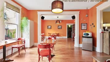 A room with a dining table, chairs, a refrigerator, and a microwave.