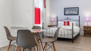 A bedroom with a bed, bedside tables, a table with chairs, and a window with curtains.