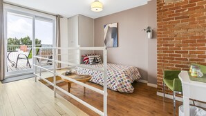 A room with a bunk bed, a small table, a chair, a potted plant, and a brick wall. - Château des Tourelles - Par Aneyro (Québec City)