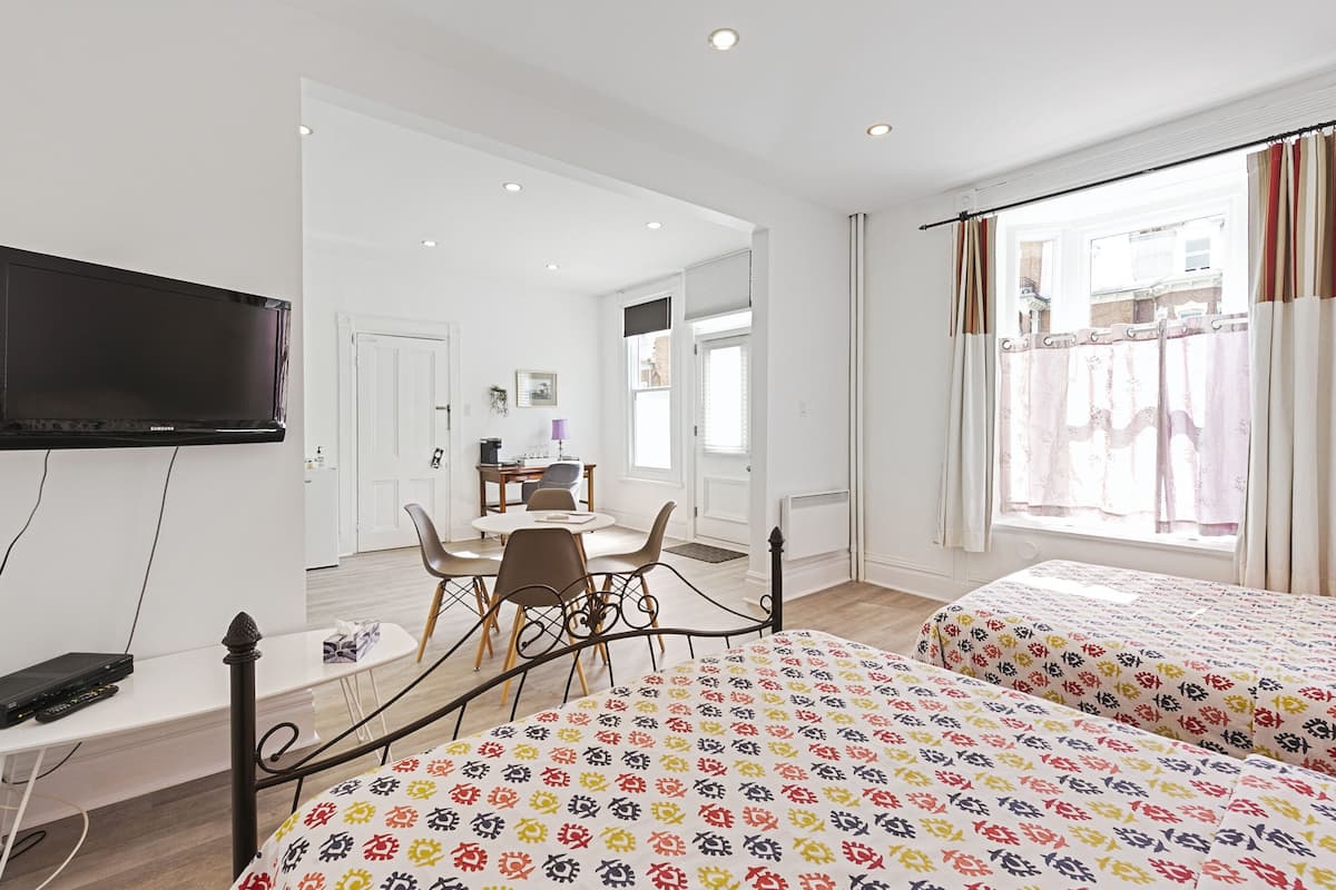 A hotel room with a bed, a desk, a TV, and a dining area.