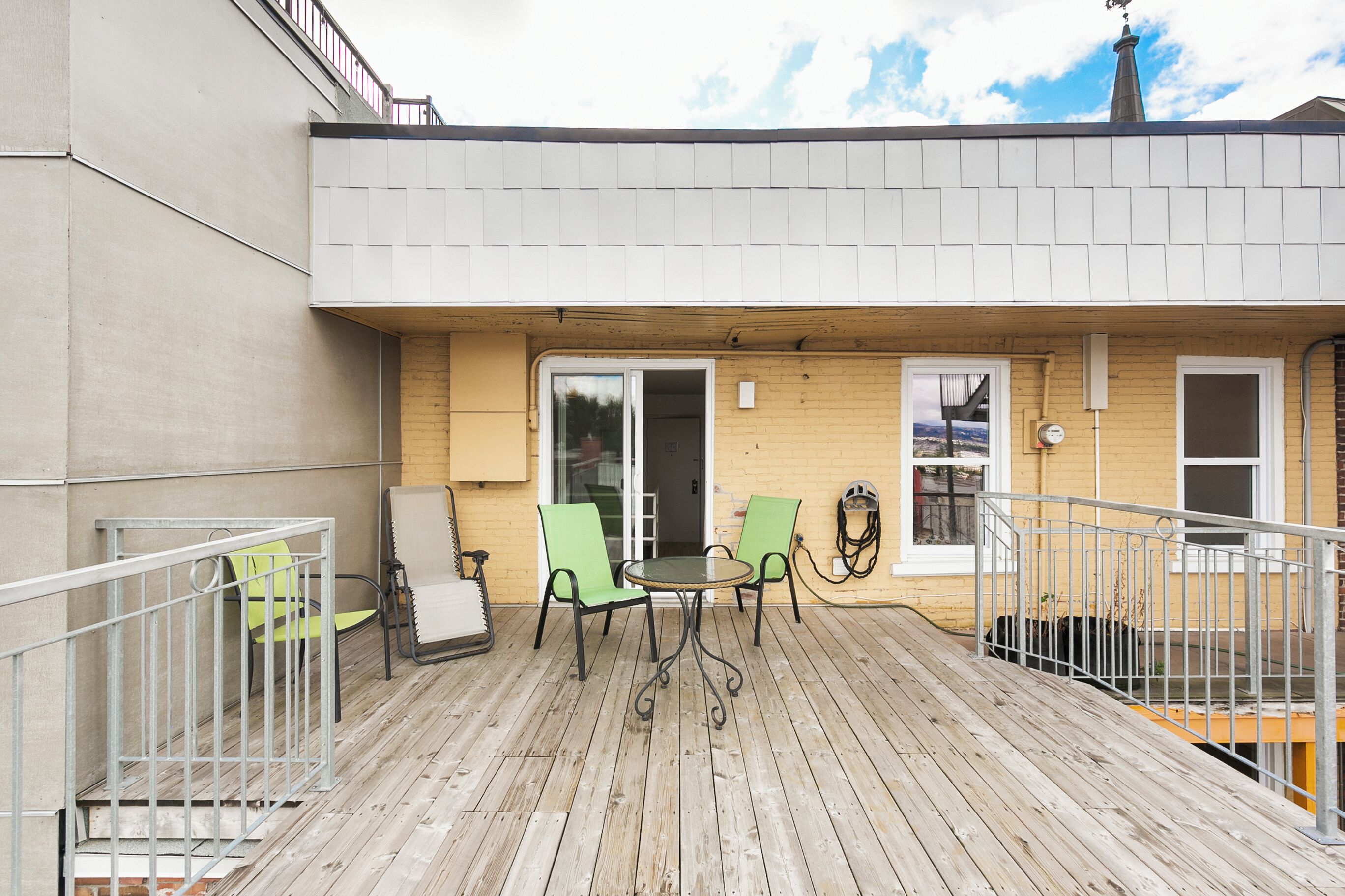 A wooden deck with outdoor seating and a view of the city.