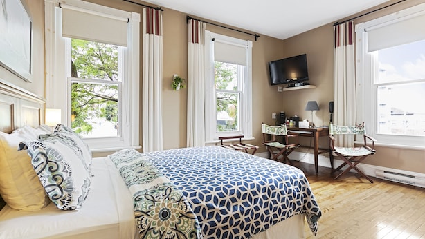 A bedroom with a large bed, a desk, and a TV. - Château des Tourelles - Par Aneyro (Québec City)