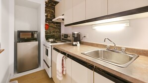 A compact kitchen with a built-in microwave, stove, and sink. - Château des Tourelles - Par Aneyro (Québec City)