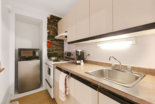 Una cocina compacta con microondas, estufa y lavabo integrados.