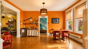 Una habitación amplia con piso de madera, una mesa de comedor con sillas, una escalera que sube a un nivel superior y vistas al exterior a través de grandes ventanales.