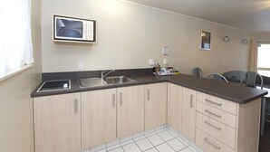 Una cocina con microondas, lavamanos y armarios.