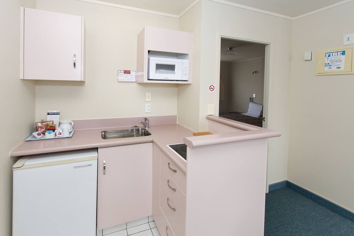 Una kitchenette compacta equipada con microondas, refrigerador pequeño y lavamanos.