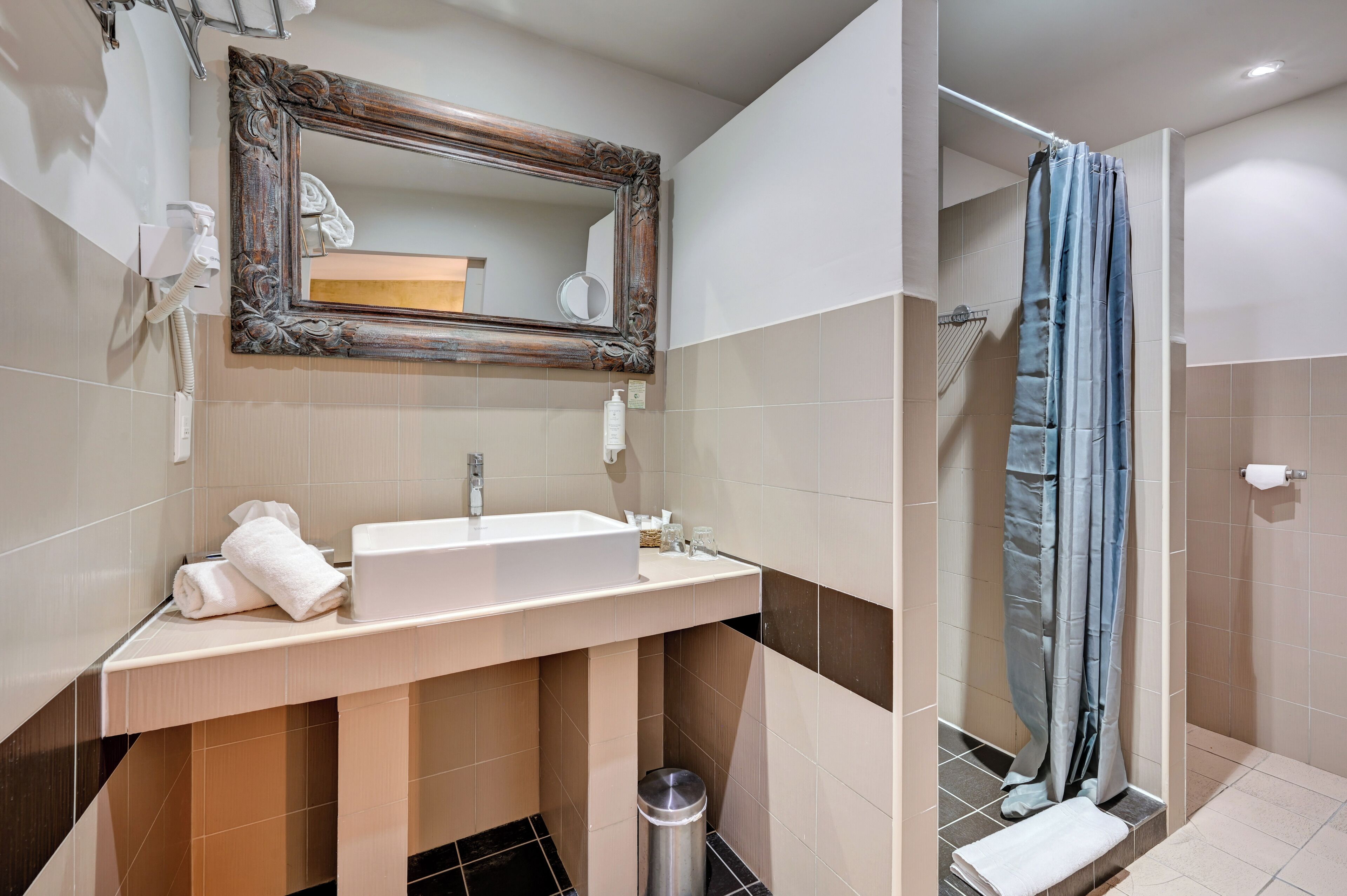 Une salle de bain avec un lavabo, un miroir et un rideau de douche.