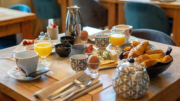 A breakfast table with various food items, drinks, and utensils.