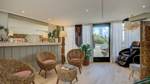 Een ruime woonkamer met rieten stoelen, een massagestoel en uitzicht op de omgeving.