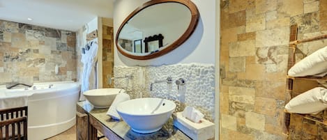 Un baño con un espejo ovalado grande, dos lavamanos, una bañera y un mueble de tocador de madera.