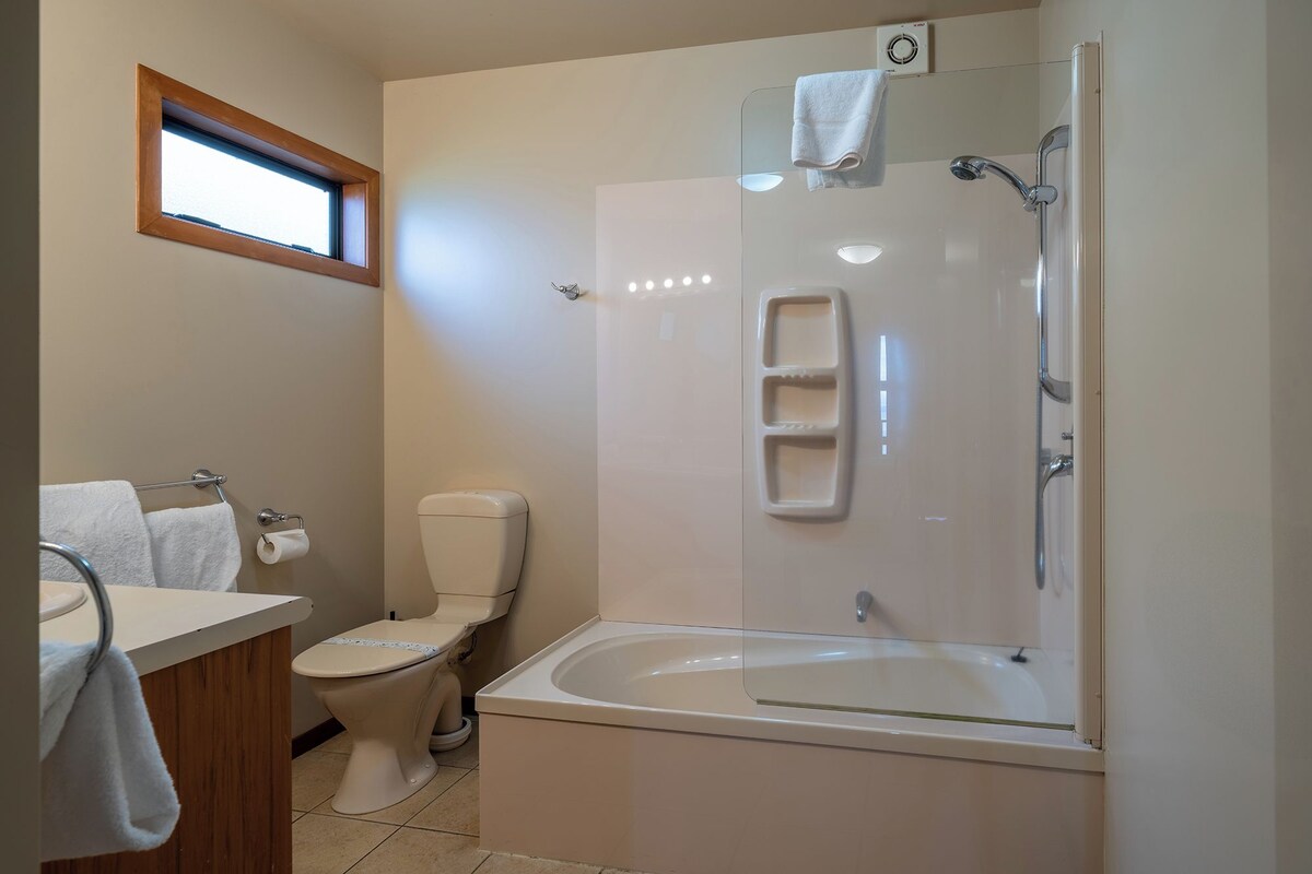 Een badkamer met toilet, wastafel, bad en douche.