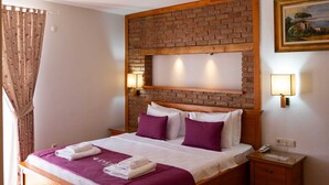 Een hotelkamer met een houten bed, een accentmuur van baksteen, een nachtkastje en een schilderij aan de muur.
