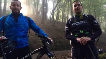 Duas pessoas ao lado de bicicletas de montanha numa área arborizada.