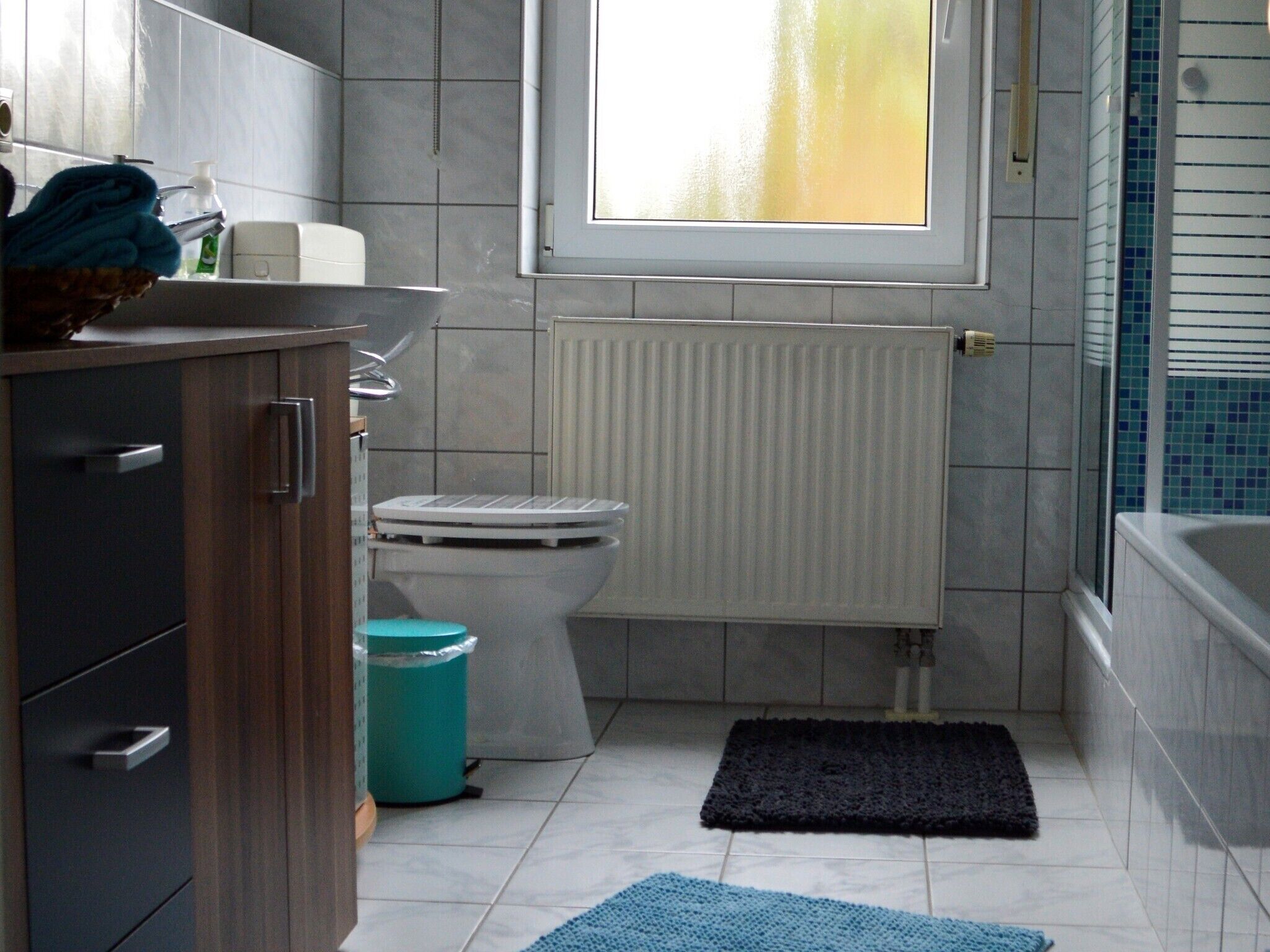 Un baño con inodoro, radiador, lavabo y ventana.