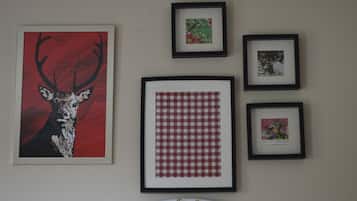 A wall with four framed pictures: a deer, a floral design, a checkered pattern, and a small floral print.