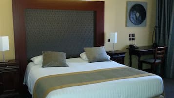 Relax in comfort with a large bed, desk, and chair, surrounded by stylish bedside tables and a wall-mounted artwork.