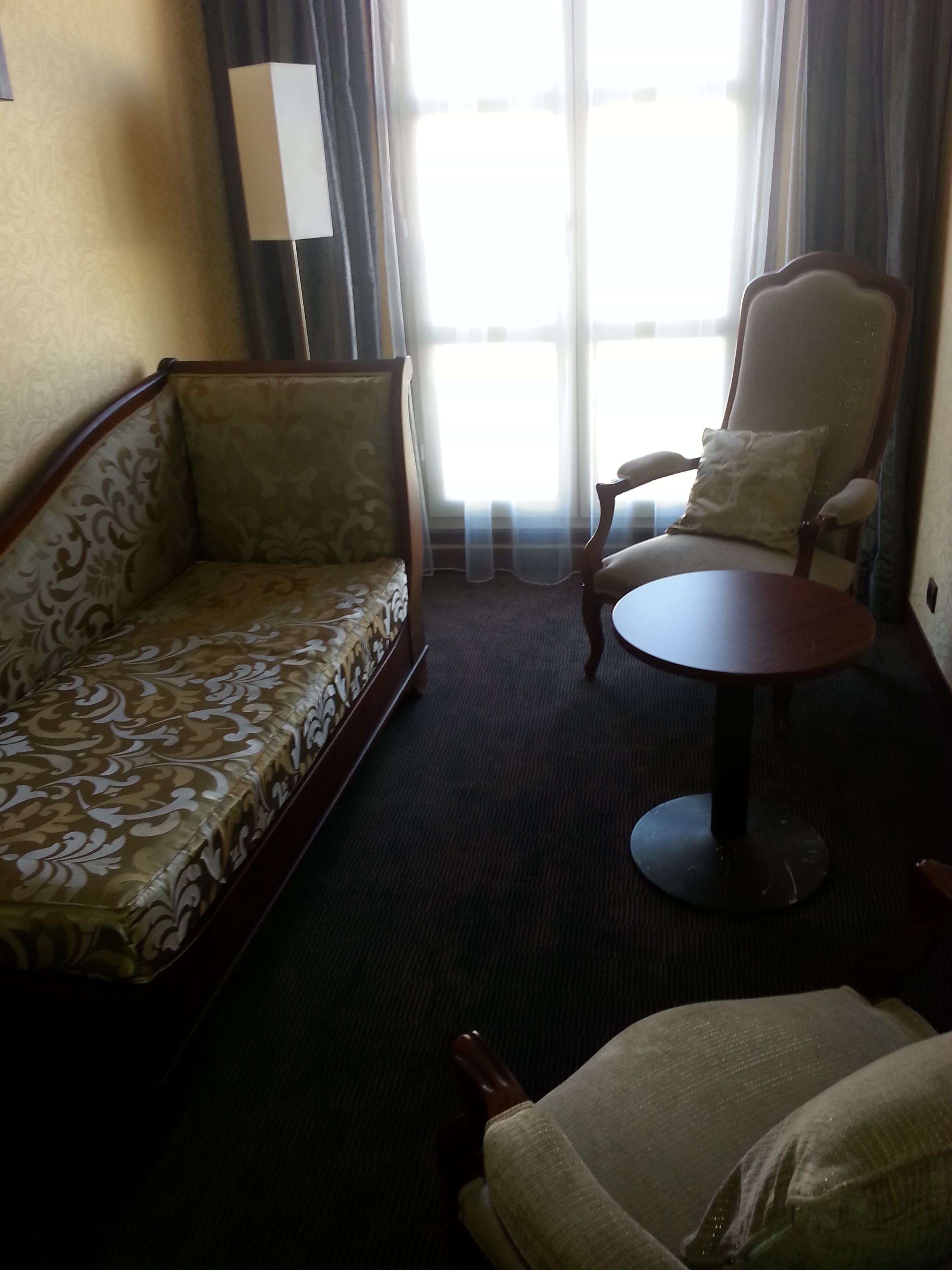 Una habitación de hotel con sofá, sillón y una pequeña mesa.