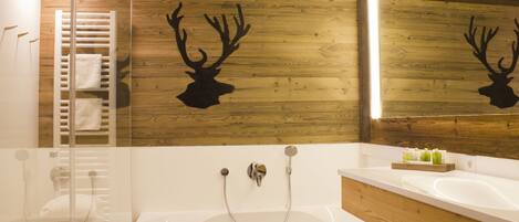 Ein Badezimmer mit Holzwänden, einem großen Spiegel, einer Badewanne und einem Waschbecken.