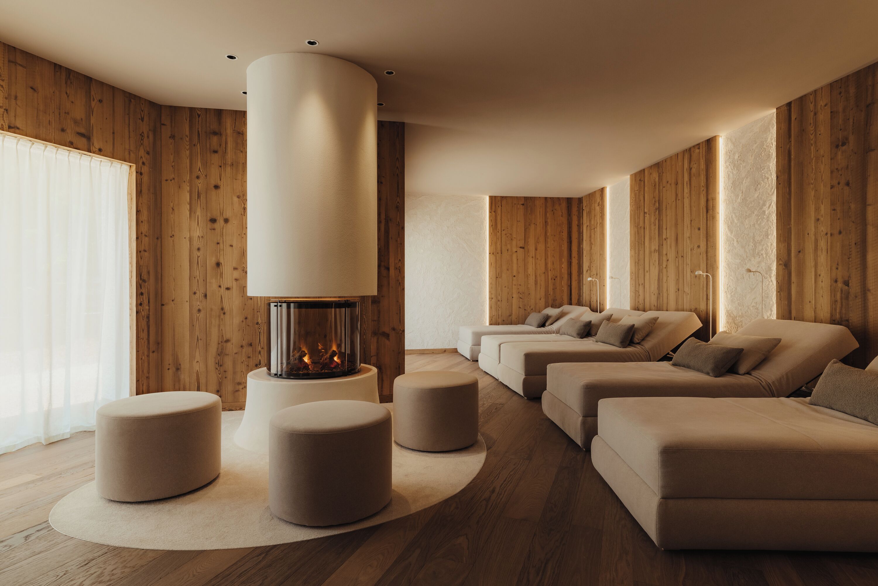 A modern living room with a fireplace, sofas, and ottomans.