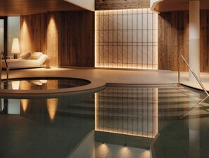 A modern indoor pool area with a wooden wall and a seating area with a lamp. - Col Alto (Corvara in Badia)