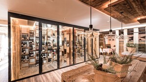 Un intérieur moderne avec un plancher en bois, des vitrines en verre où sont exposées des bouteilles de vin, et un banc en bois agrémenté d’une plante.